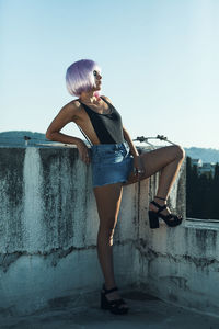 Hipster standing on building terrace against sky