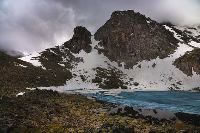 Calm landscape with snowy mountains in the clouds and mountain lakes in ice. mystical rocky