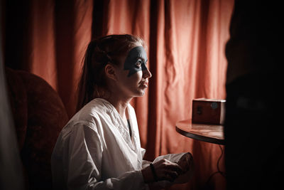 Young woman using mobile phone while sitting in mirror