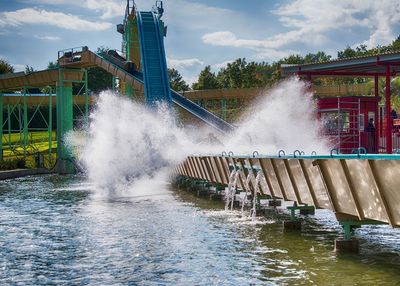 Water splashing on bridge against sky