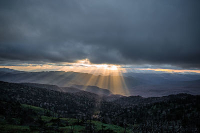 Sunlight streaming through clouds over landscape