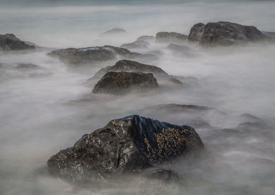 Scenic view of rock formation in sea against sky