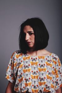 Portrait of beautiful young woman standing against gray background