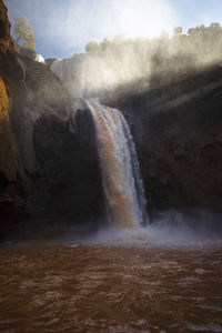 Scenic view of waterfall against sky