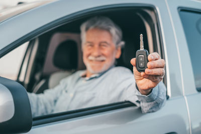 Portrait of senior man holding car key while sitting in car