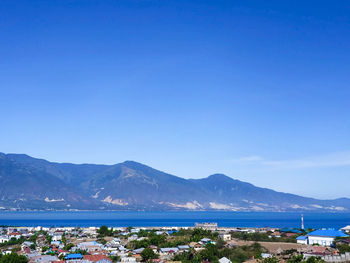 Scenic view of sea and mountains against clear blue sky