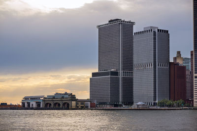 Building by river against sky during sunset