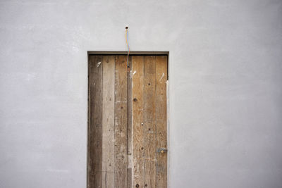 Closed wooden door amidst gray wall