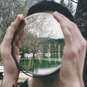 Reflection of man on lake against trees