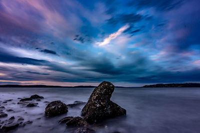 Rocks in sea against sky during sunset