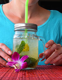 Midsection of woman having mojito at table