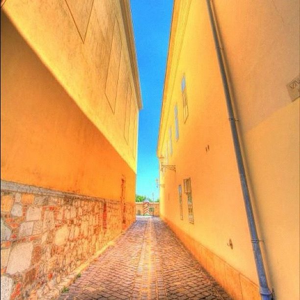 architecture, built structure, building exterior, the way forward, diminishing perspective, narrow, alley, building, clear sky, vanishing point, city, wall - building feature, residential structure, street, cobblestone, residential building, low angle view, day, outdoors, brick wall