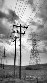 Low angle view of electricity pylon against cloudy sky
