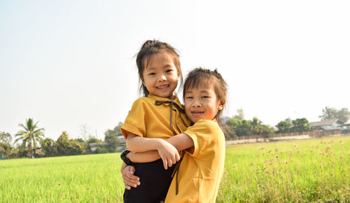 Portrait of smiling boy on field against sky