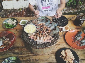 Midsection of man eating seafood served on wooden table