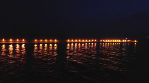 Illuminated beach against clear sky at night