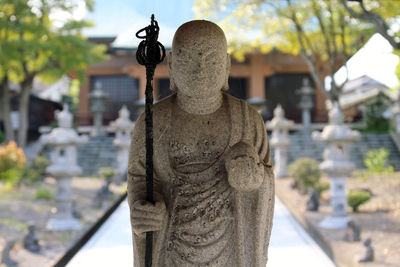 Close-up of statue against cemetery