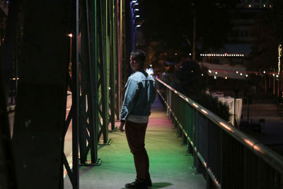 Side view of man walking on footpath at night