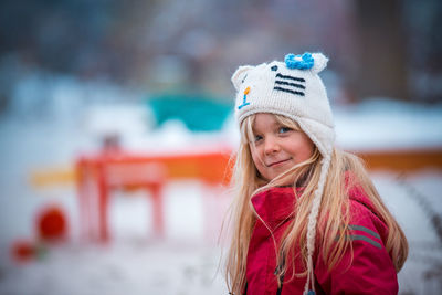 Side view portrait of girl smiling while standing on field during winter