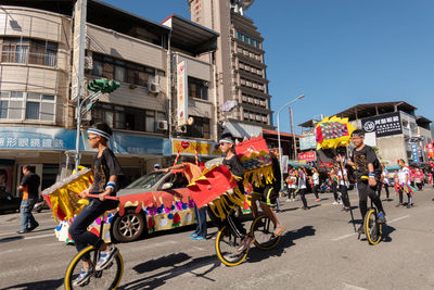 People riding bicycles on street against buildings in city