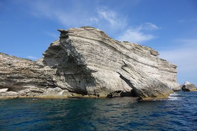 Rock formations by sea against blue sky