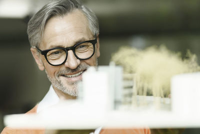 Portrait of smiling man looking at architectural model