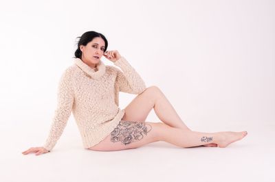 Portrait of young woman sitting against white background