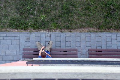 Boy sitting on bench with mobile phone, directly above