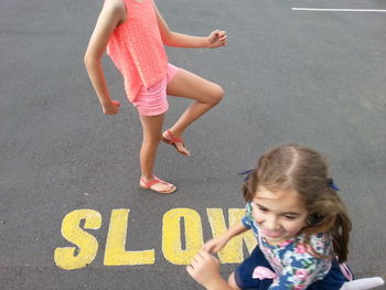 High angle view of siblings by slow sign on road