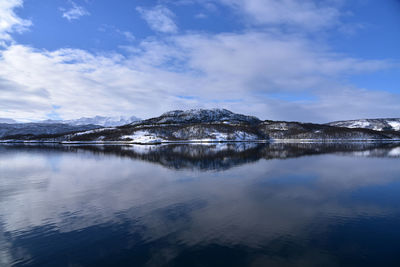 Scenic view of lake by snowcapped mountains against sky