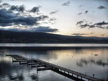 Pier on lake against cloudy sky