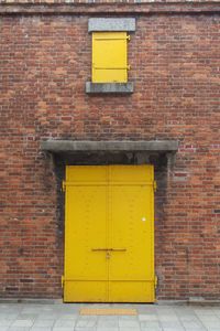 Yellow door on brick wall of building