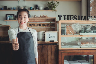 Smiling owner showing thumbs up in store