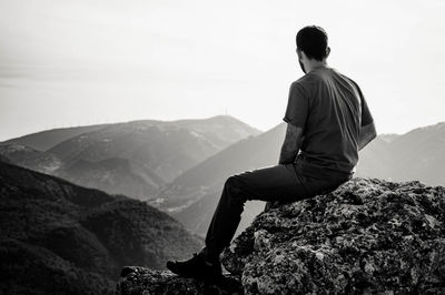 Rear view of man looking at mountains against sky