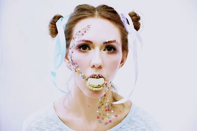 Close-up portrait of young woman with macaroon in mouth