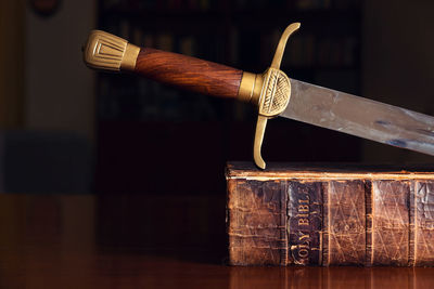 Close-up of sword with book at table