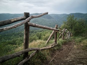 Wooden fence on landscape against sky