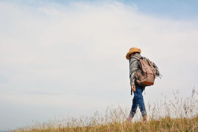 Girl walking on grassy field against sky