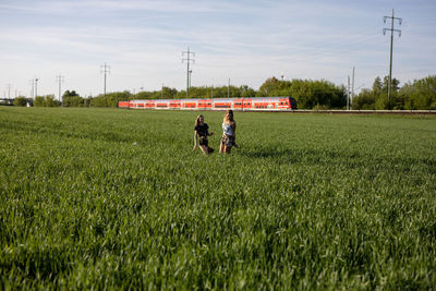 Friends standing on grassy field against sky