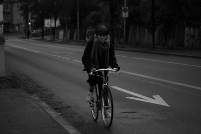 Woman riding bicycle on road in city