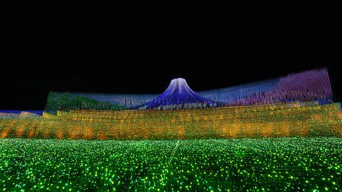 Illuminated field against sky at night