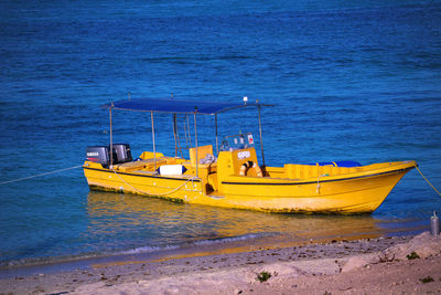 Yellow boat moored on beach against sky