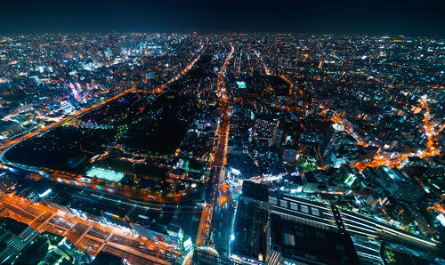 High angle view of illuminated city against sky at night