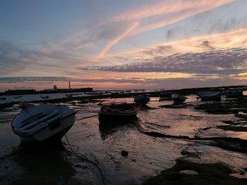 Boats moored on sea against sky during sunset