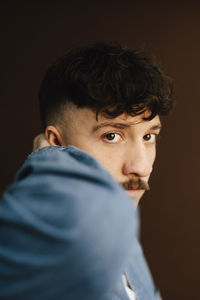 Portrait of man with hand behind head in studio