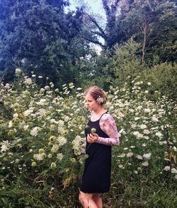 Young woman using mobile phone while standing on tree