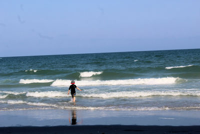 Full length of woman standing on beach against sky