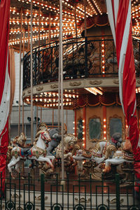 Children ride horses and teddy bear on children's carousels in an amusement park.