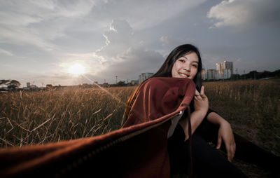 Beautiful young woman in field against sky