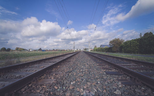 Surface level of railway tracks against cloudy sky